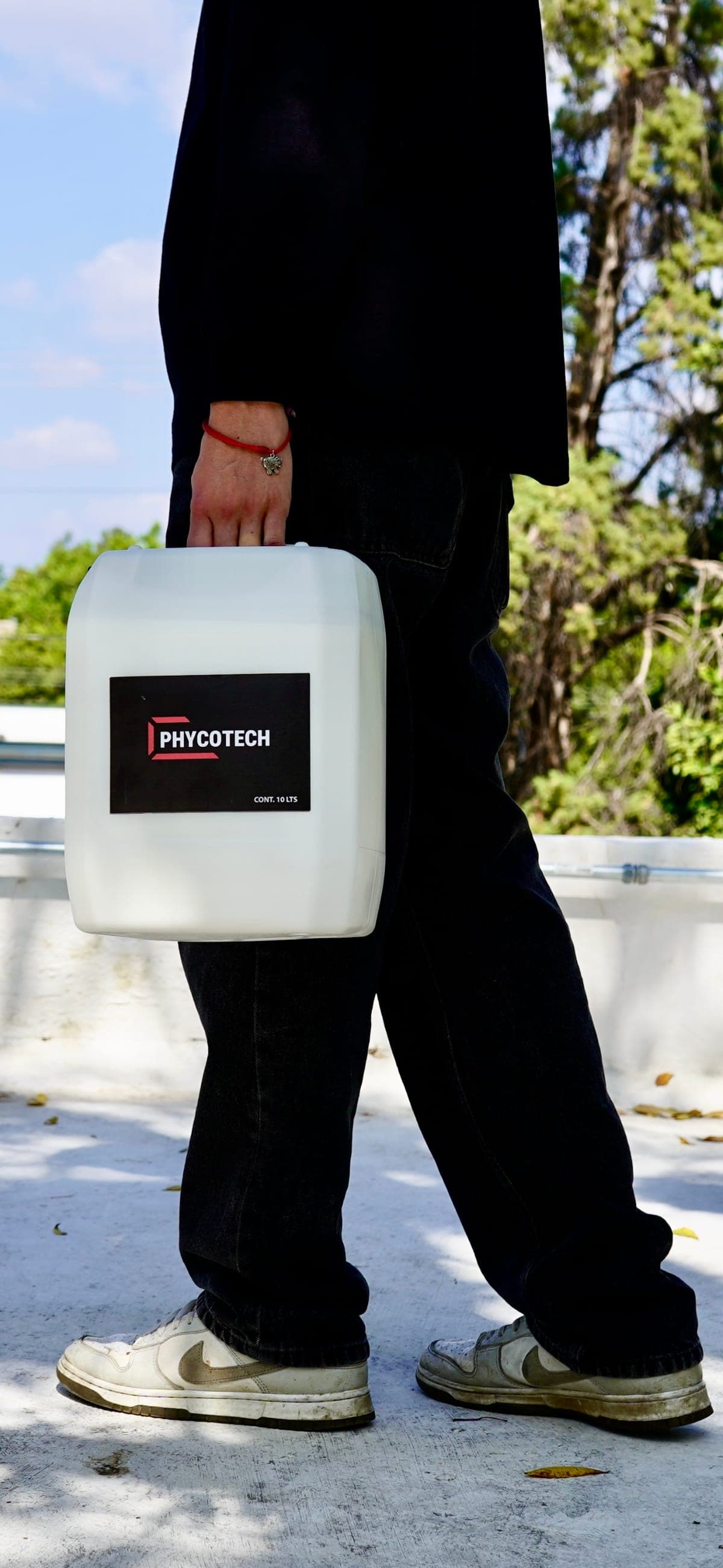 Aplicador trasladando un envase de PHYCOTECH de 10 litros en obra
