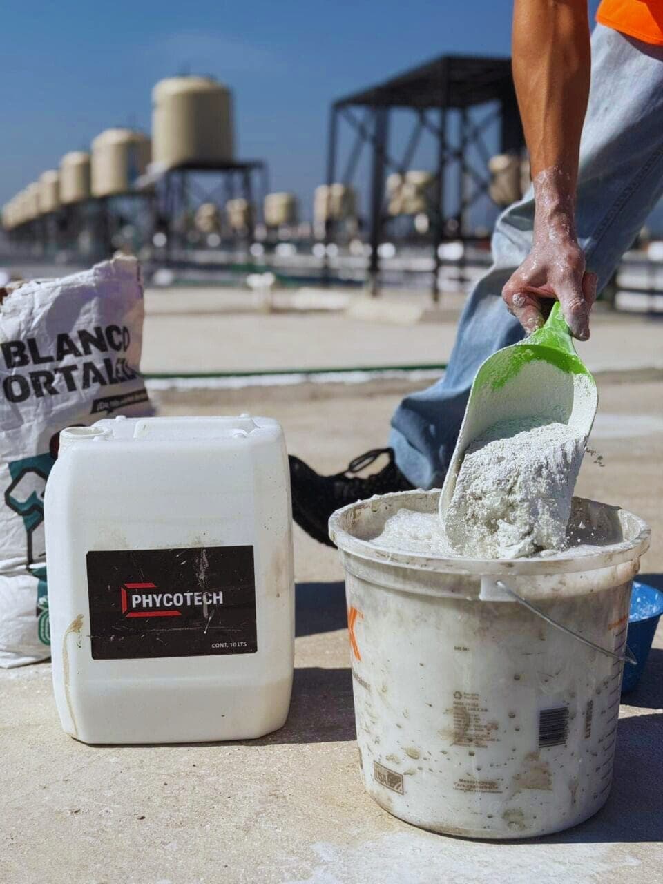 Preparación de la mezcla en obra: cemento vertido en una cubeta junto a un envase de PHYCOTECH